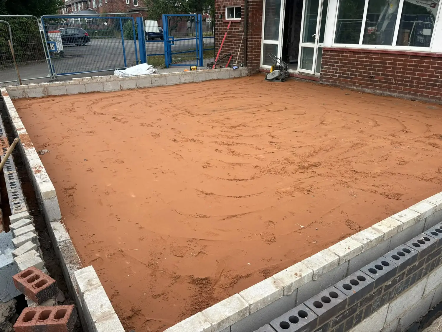 Sand blinding levelled inside a new concrete block perimeter wall ready for the slab